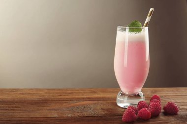 Lezzetli berry milkshake ve taze ahududu ahşap masa ve gri arka plan üzerinde cam