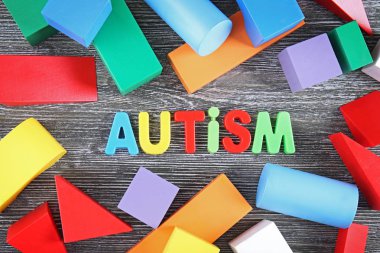 Ahşap arka plan üzerinde renkli figürleriyle Word otizm