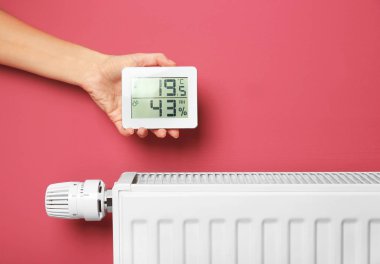 Pil Isıtma yakınındaki elektronik termometre tutan el