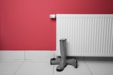Radyatör pembe bir arka plan üzerinde Isıtma yakınındaki gumboots