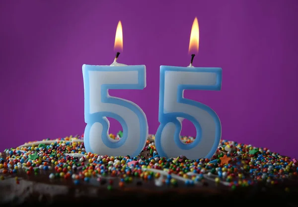 Tarta de cumpleaños con velas encendidas sobre fondo púrpura — Foto de Stock