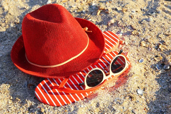 Sombrero rojo, sandalias y gafas de sol sobre arena —  Fotos de Stock