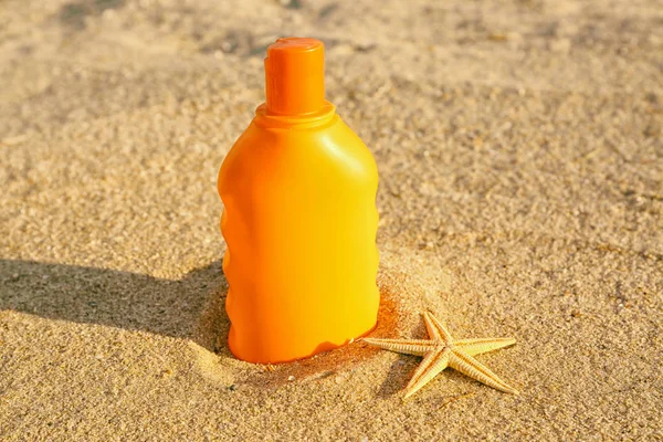 Sunscreen cream and starfish on sea coast, close up view — Stock Photo, Image