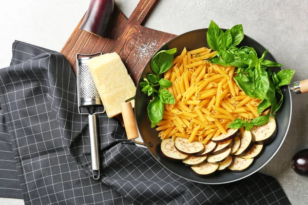 Sartén con ingredientes para pasta sabrosa, servilleta, tablero de cocina y rallador en mesa gris, vista superior — Foto de Stock
