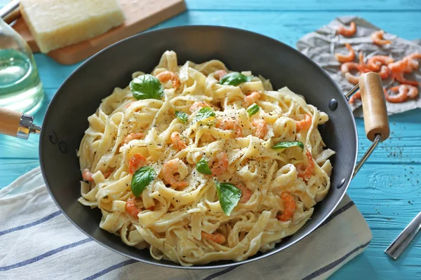 Pan with alfredo pasta and napkin on wooden table — Stock Photo, Image