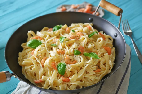 Pan with tasty alfredo pasta, fork and napkin on wooden table — Stock Photo, Image