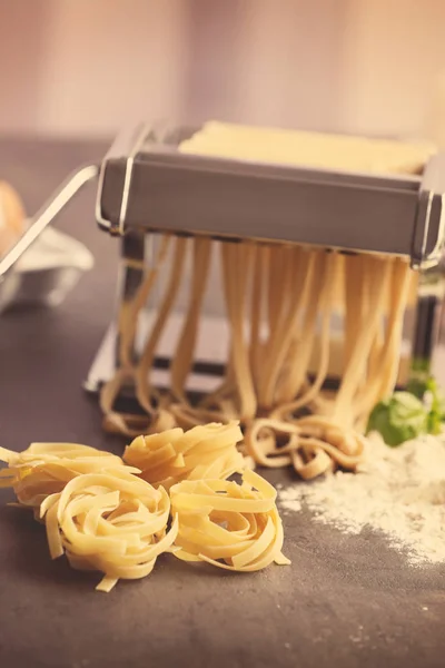 Hacer tagliatelle con máquina de pasta en la mesa de la cocina —  Fotos de Stock