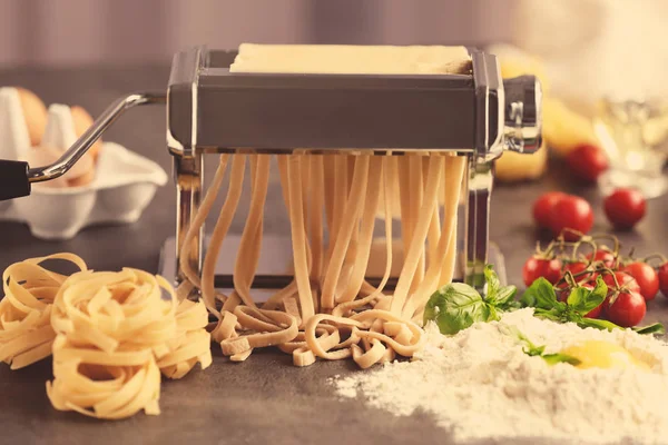 Making tagliatelle with pasta machine on kitchen table — Stock Photo, Image