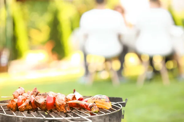 Tasty meat and vegetables on barbecue grill against blurred background, close up view — Stock Photo, Image