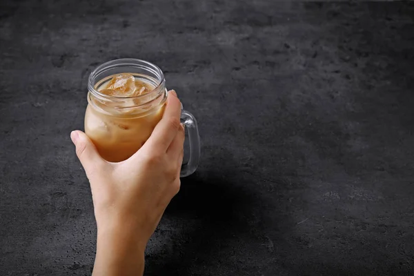 Wanita memegang gelas cangkir es kopi dengan susu di latar belakang abu-abu — Stok Foto