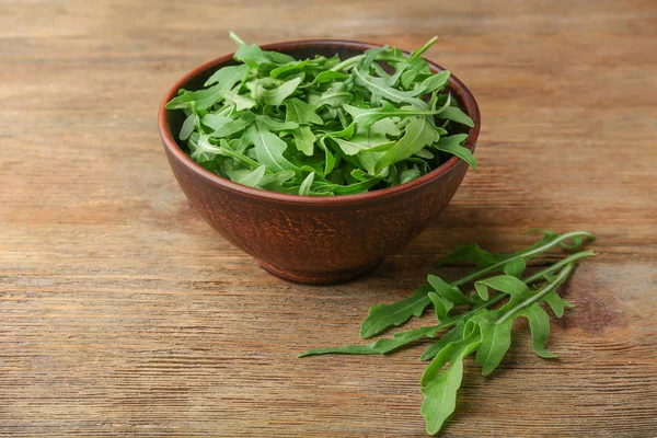 Arugula in a bowl on wooden table — Stock Photo, Image
