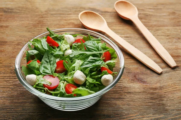 Fresh healthy salad in a glass bowl on wooden table — Stock Photo, Image