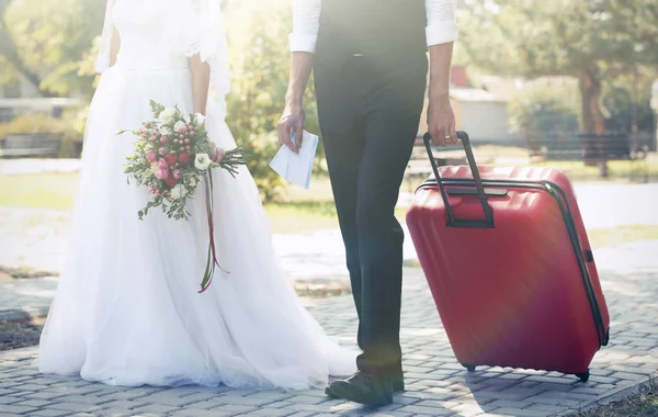 Braut und Bräutigam mit großem Koffer im Freien — Stockfoto