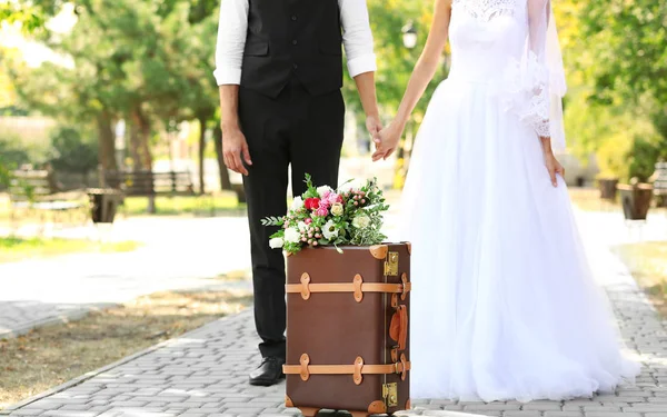 Vintage koffer en bruidegom met bruid op achtergrond — Stockfoto