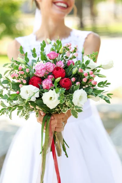 Jonge bruid met boeket bloemen in park — Stockfoto