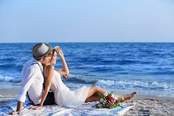 Joven pareja feliz sentado en la playa — Foto de Stock