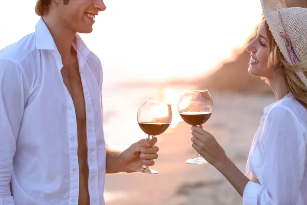 Молодая счастливая пара пьет красное вино на берегу моря, крупным планом — стоковое фото