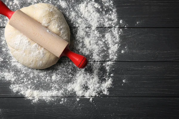 Dough untuk pizza dan rolling pin dengan tepung di atas meja kayu — Stok Foto