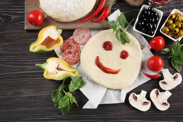 Massa de pizza crua com ingredientes na mesa de madeira — Fotografia de Stock