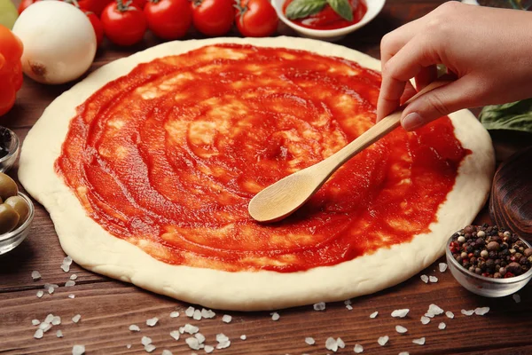 Kvinnlig hand kladda sås på pizzadeg, närbild — Stockfoto