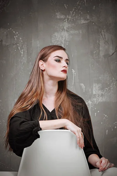 Jonge prachtige vrouw in zwarte shirt met mooie make-up poseren op een grijze achtergrond — Stockfoto