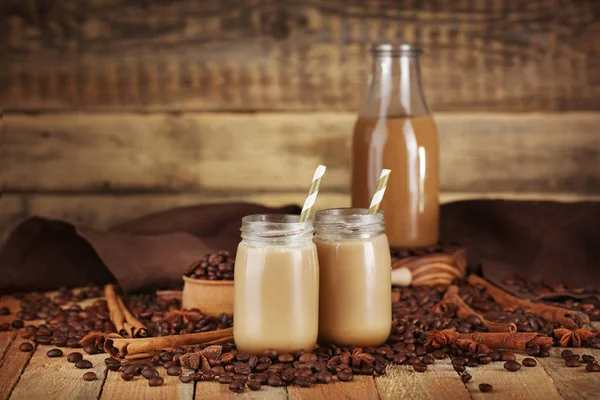 Toples kaca dengan makanan penutup susu lezat dan biji kopi di atas meja, closeup — Stok Foto