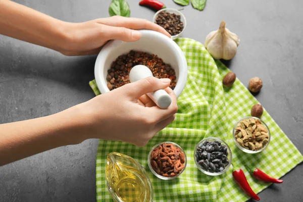 Female hands grinding spices in mortar — Stock Photo, Image