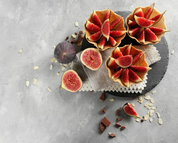 Paniers savoureux avec des figues fraîches sur serviette sur fond clair, vue de dessus — Photo