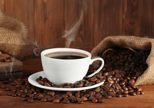 Kopje verse koffie en zak met bonen, close-up — Stockfoto