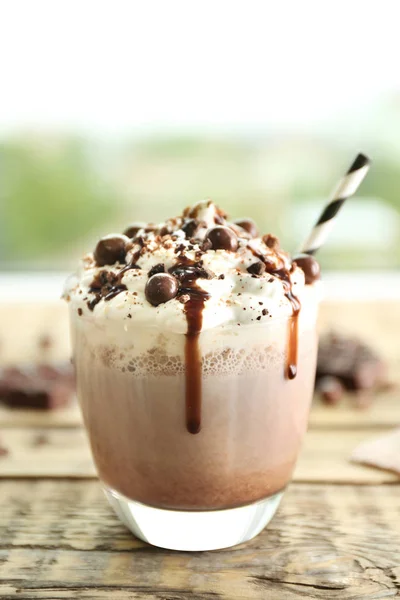 Läcker mjölk efterrätt med choklad på träbord och suddig bakgrund — Stockfoto