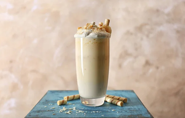 Delicioso batido de plátano con dulces sobre mesa azul y fondo beige —  Fotos de Stock