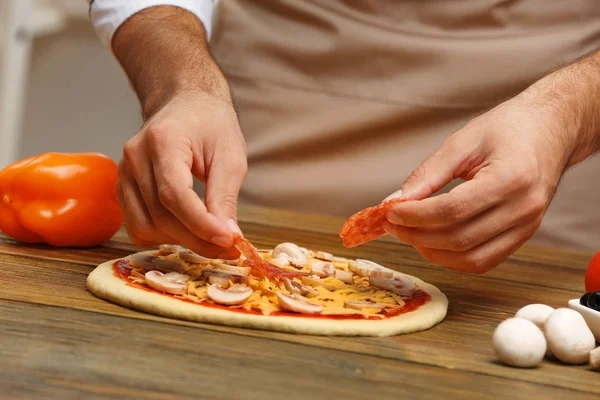 Manos masculinas preparando pizza en primer plano de mesa de madera —  Fotos de Stock