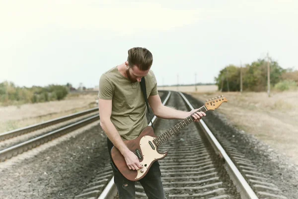 Schöner Mann mit Gitarre auf der Eisenbahn — Stockfoto