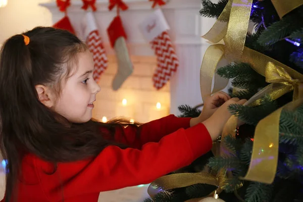 Niña decorando el árbol de Navidad, sobre fondo borroso —  Fotos de Stock