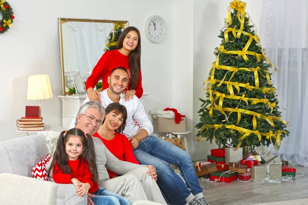 Ευτυχισμένη οικογένεια κάθεται στον καναπέ στο σαλόνι διακοσμημένο για τα Χριστούγεννα — Φωτογραφία Αρχείου