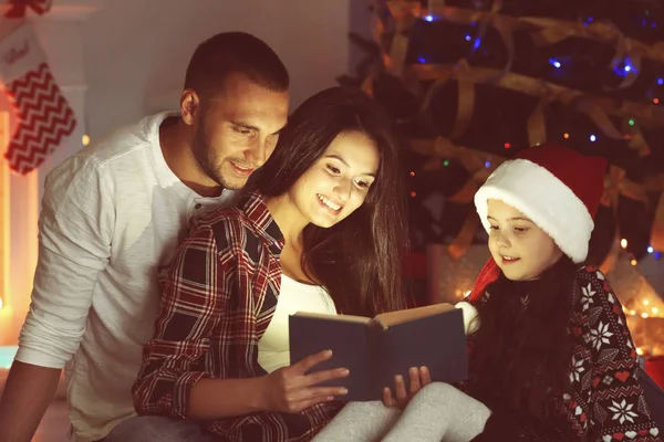 Bambina e la sua famiglia libro di lettura in soggiorno decorato per Natale — Foto Stock