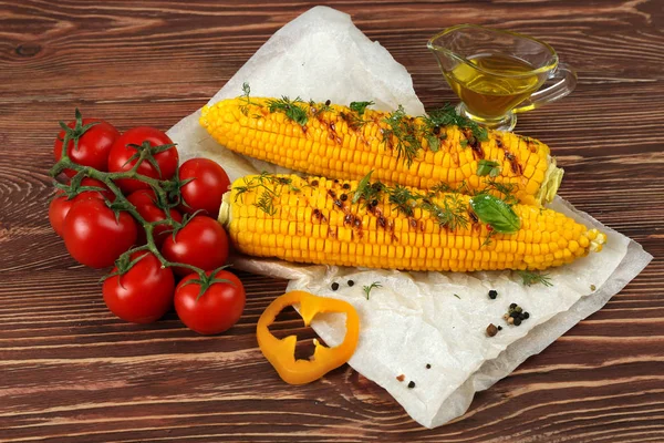 Grilled corns with cherry tomatoes and ingredients on wooden table — Stock Photo, Image