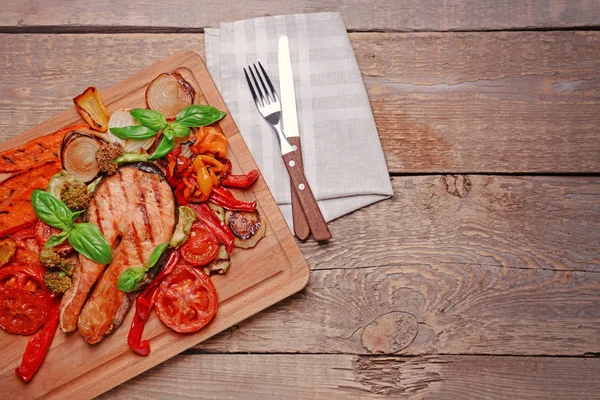 Grilovaná zelenina s plátkem červené ryby na dřevěném prkénku — Stock fotografie