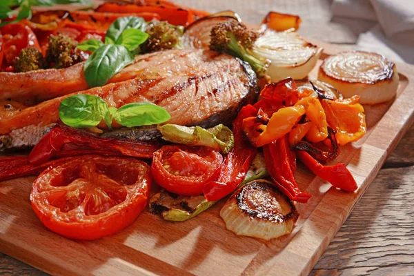 Grilled vegetables with slice of red fish on wooden cutting board, closeup — Stock Photo, Image