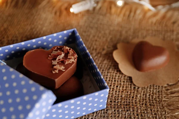 Schachtel mit Schokoladenherzen auf sackigem Hintergrund — Stockfoto