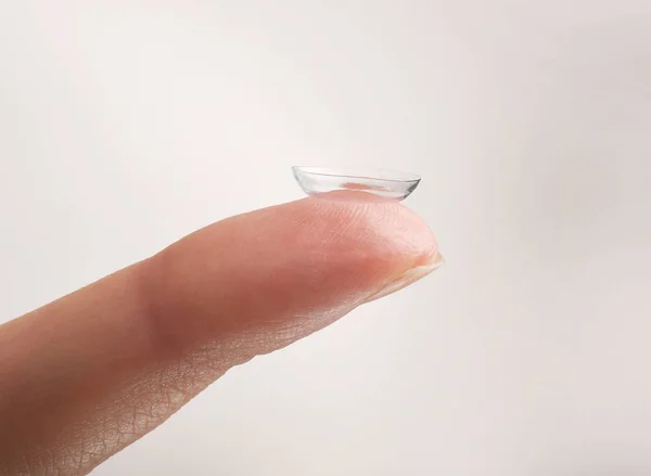 Contactlens op vrouwelijke vinger tegen de lichte achtergrond, close-up. Geneeskunde en visie concept — Stockfoto