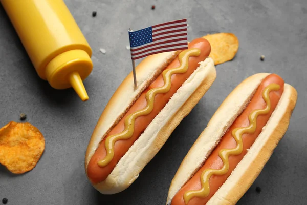 Cachorros-quentes com mostarda e pequena bandeira dos EUA em fundo cinza — Fotografia de Stock