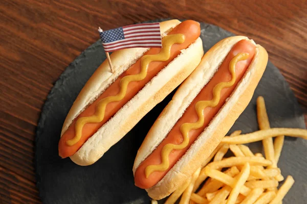 Sosisli sandviç kayrak plaka üzerinde hardal ve küçük ABD bayrağı ile — Stok fotoğraf