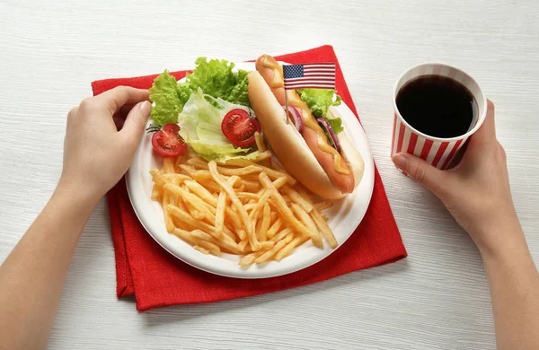 Donna con hot dog, patatine fritte e cola su fondo di legno — Foto Stock