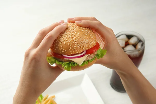 Woman eating burger and cola on background