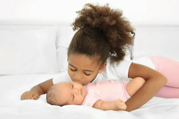 Cute baby and elder sister on bed — Stock Photo, Image