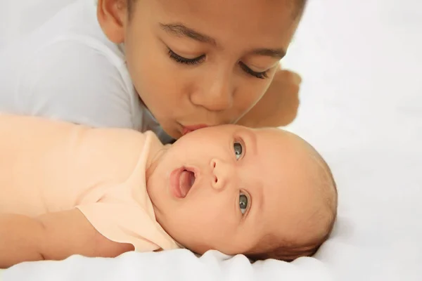 Cute baby and elder sister on bed — Stock Photo, Image