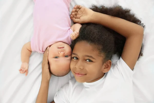 Cute baby and elder sister on bed — Stock Photo, Image