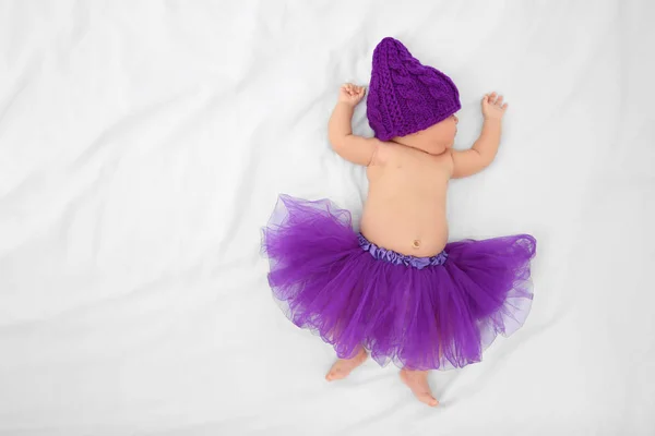 Симпатичный ребенок в фиолетовой юбке спит на кровати — стоковое фото