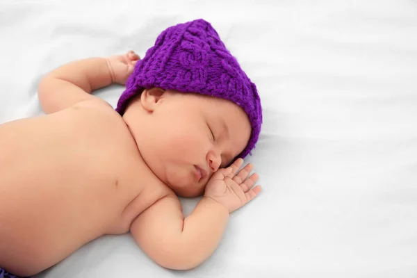 Lindo bebé en sombrero púrpura durmiendo en la cama — Foto de Stock